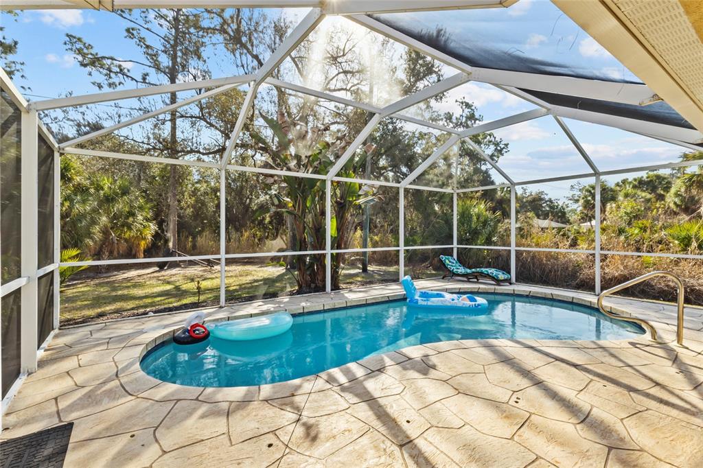 A screened-in swimming pool with a stone deck and a view of trees outside — 136 OVERBROOK STREET, PORT CHARLOTTE, FL