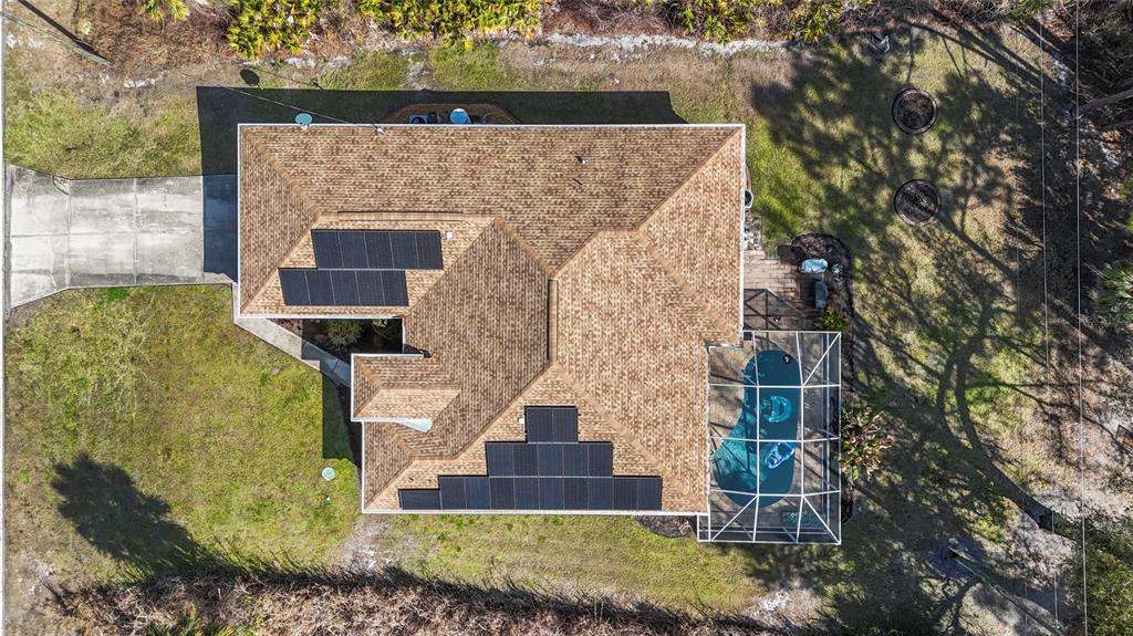An aerial view shows a house with solar panels on the roof and a screened pool — 136 OVERBROOK STREET, PORT CHARLOTTE, FL