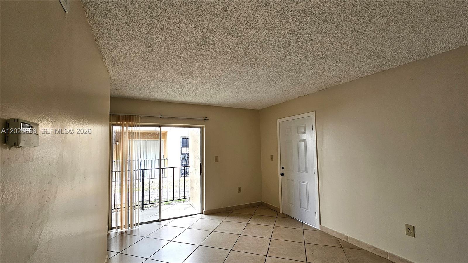 An empty room features a sliding glass door, a white entry door, and tiled floors — 1235 NW 6th St # 3, Miami FL 33125, MIAMI, FL