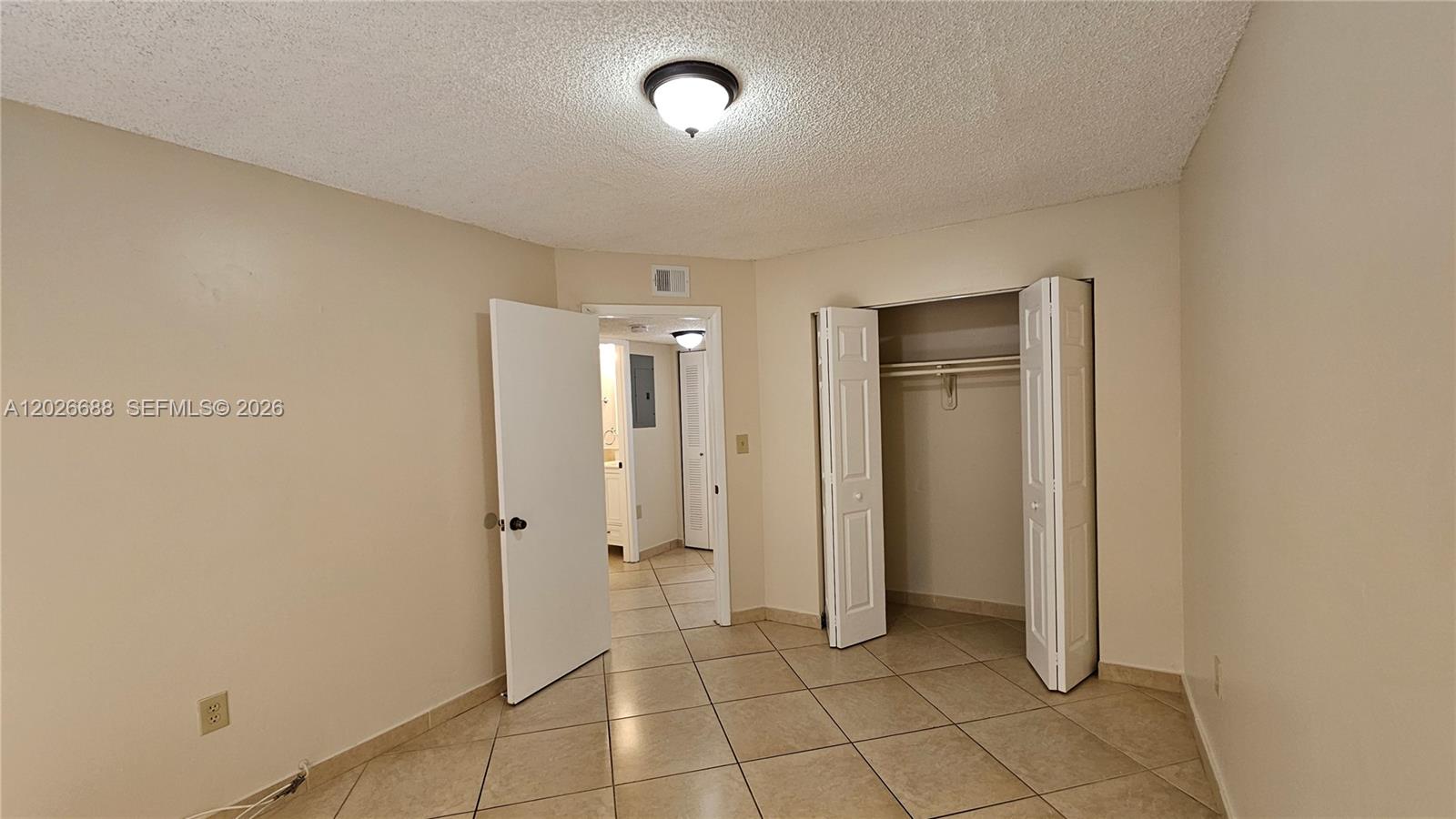 An empty bedroom features beige walls, tile flooring, a closet, and a doorway to a hallway — 1235 NW 6th St # 3, Miami FL 33125, MIAMI, FL