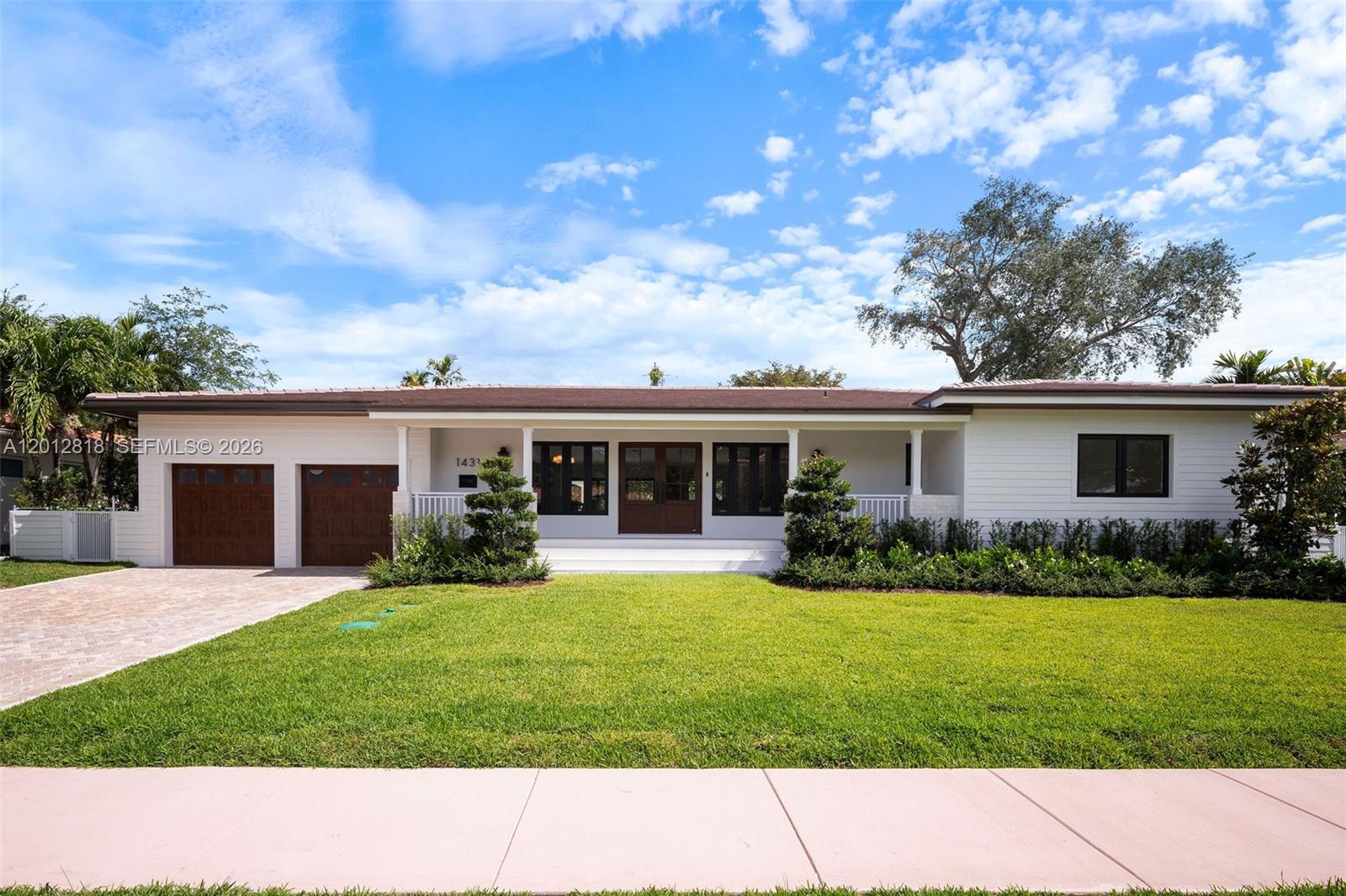A single-story white house features a brown roof, wooden garage doors, and a front lawn — 1431 Certosa Ave, Coral Gables FL 33146, CORAL GABLES, FL