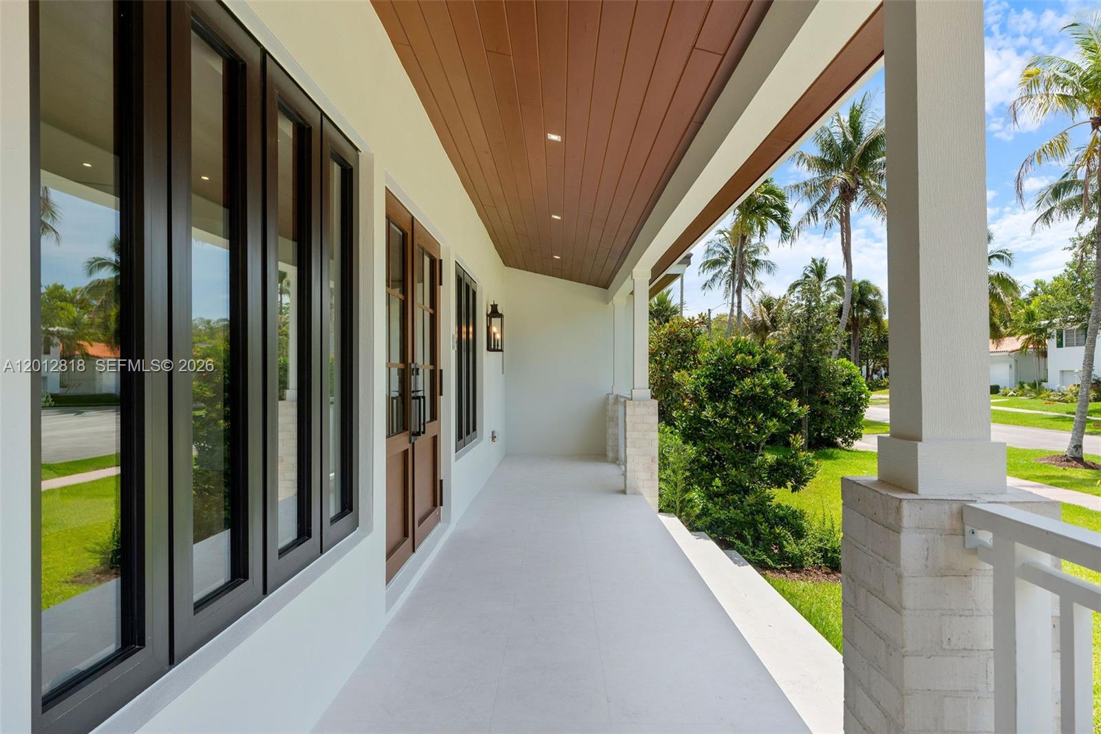 A covered porch features a wood-paneled ceiling, white tile flooring, and dark-framed windows and doors — 1431 Certosa Ave, Coral Gables FL 33146, CORAL GABLES, FL