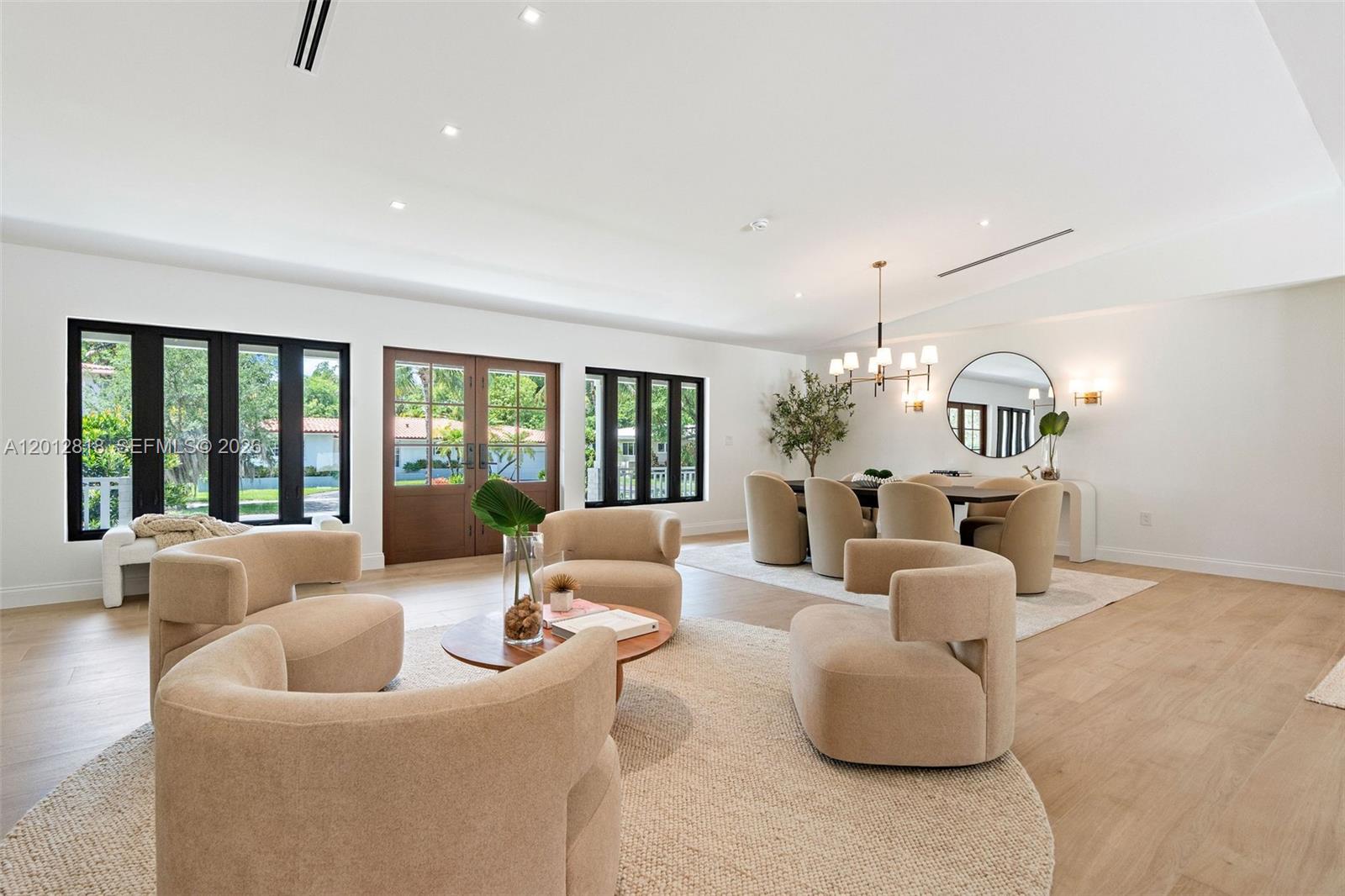 A bright, open-concept living and dining area features neutral furniture, light wood floors, and windows — 1431 Certosa Ave, Coral Gables FL 33146, CORAL GABLES, FL