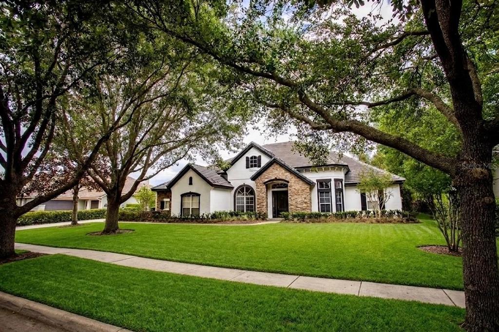 A single-story house with a stone facade, white stucco walls, and a large front lawn — 25609 HAWKS RUN LANE, SORRENTO, FL