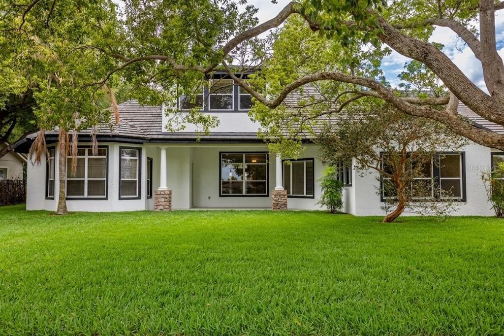 The backyard view shows a white two-story house with black-trimmed windows and a green lawn — 25609 HAWKS RUN LANE, SORRENTO, FL
