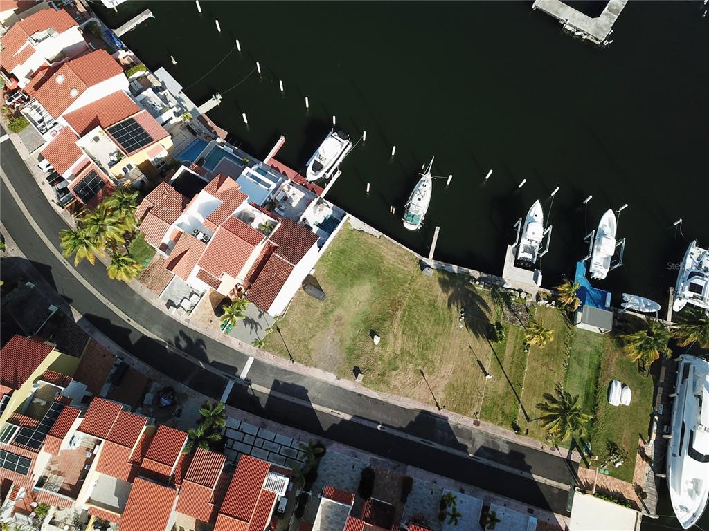 An aerial view shows a vacant waterfront lot situated between residential buildings and boat slips — SAN MIGUEL 47, HUMACAO, PR