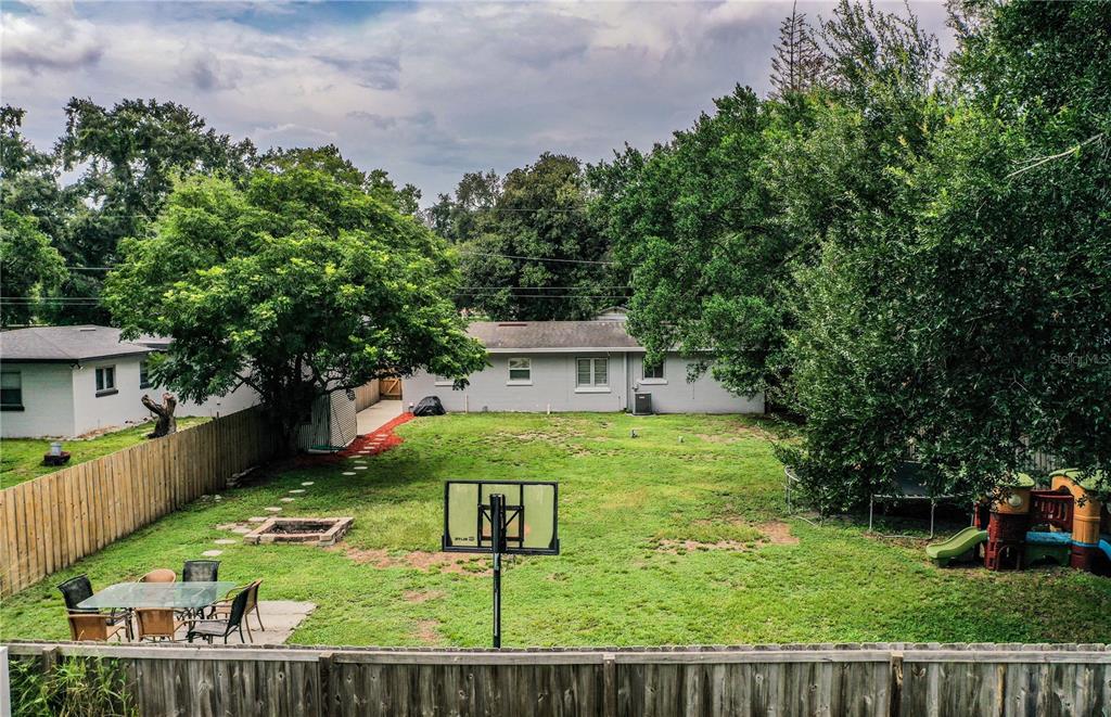 A backyard features a basketball hoop, a patio set, a fire pit, and a playground — 3004 AVENUE S NW, WINTER HAVEN, FL