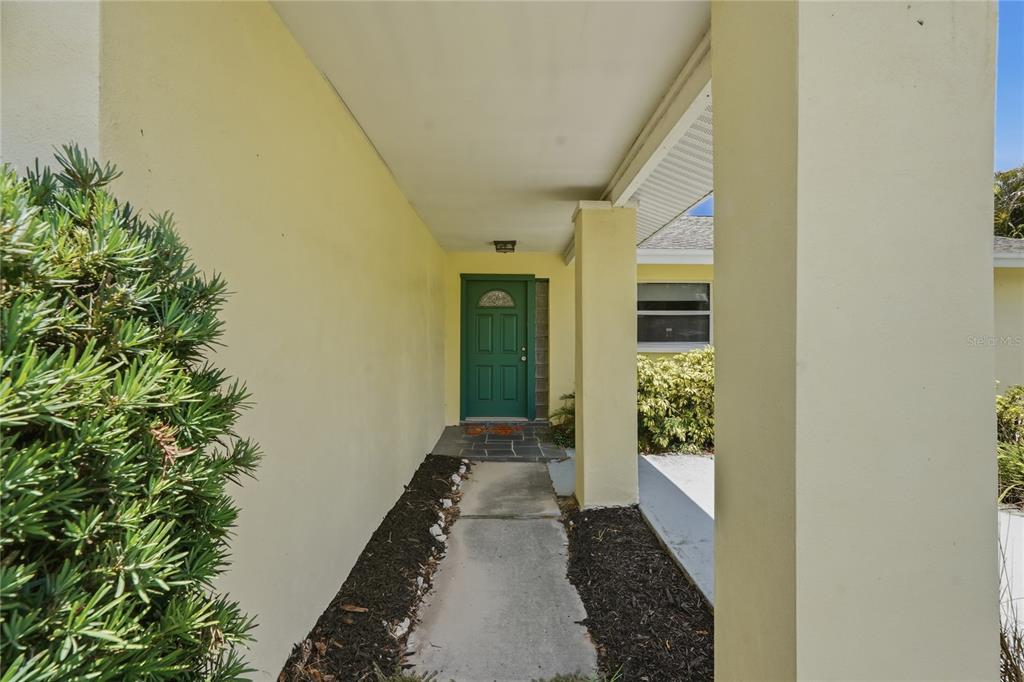 A concrete walkway leads to a green front door under a covered entryway — 1634 DALE CIRCLE N, DUNEDIN, FL