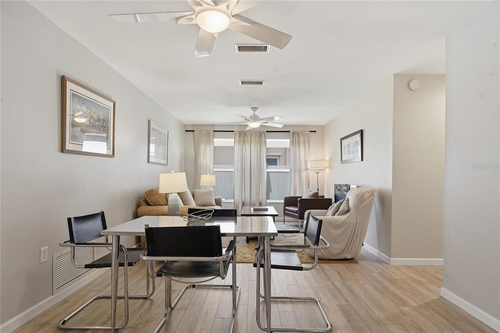 A dining area with a metal table and chairs opens into a living room — 1634 DALE CIRCLE N, DUNEDIN, FL