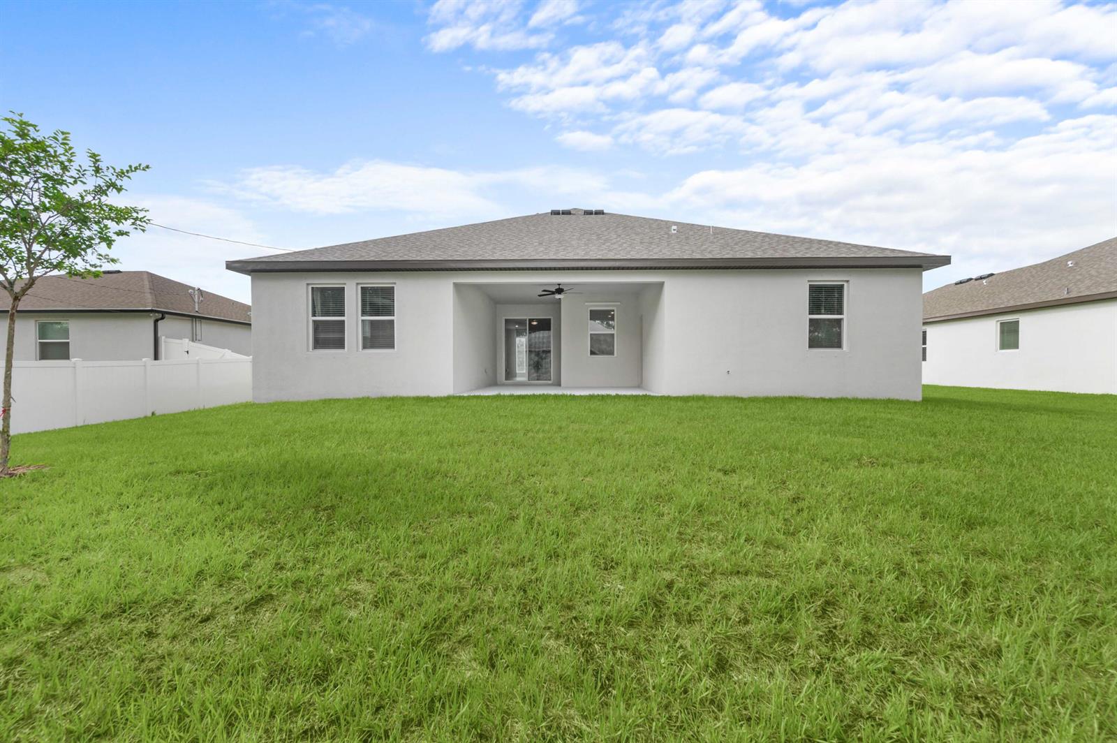 The rear exterior of a single-story house features a covered patio and a grassy yard — 7876 104th Avenue, Vero Beach FL 32967, VERO BEACH, FL