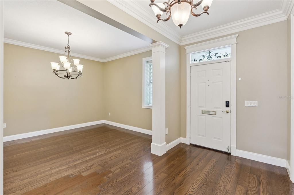 An entryway and dining area feature hardwood floors, crown molding, and two hanging chandeliers — 5210 HAMMOCK CIRCLE, ST CLOUD, FL