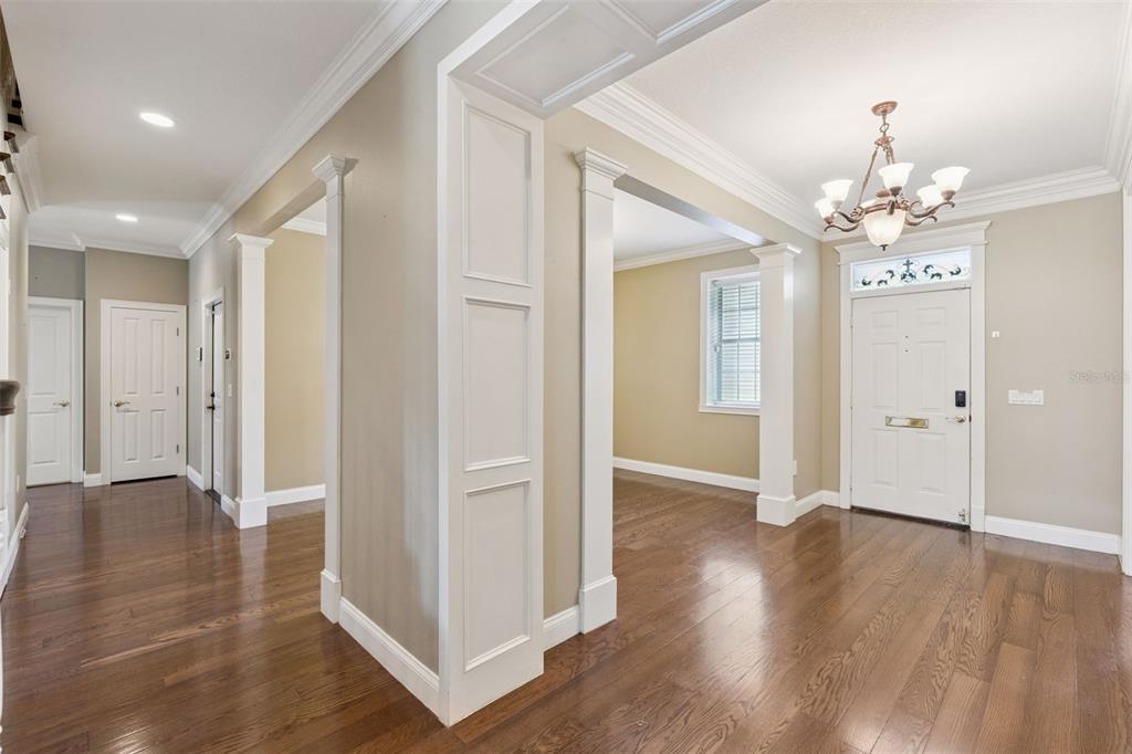 An entryway with hardwood floors, white trim, and a chandelier leads to adjacent rooms — 5210 HAMMOCK CIRCLE, ST CLOUD, FL
