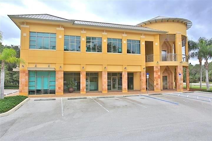 A two-story yellow commercial building with a curved corner and a paved parking lot — 6 MERIDIAN HOME LANE UNIT 101, PALM COAST, FL