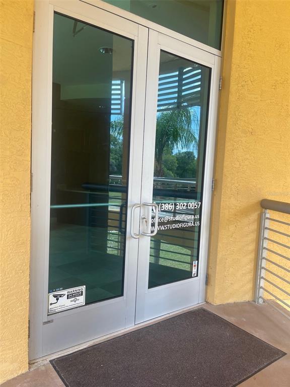 A set of double glass doors with metal frames leads into a building entrance — 6 MERIDIAN HOME LANE UNIT 101, PALM COAST, FL