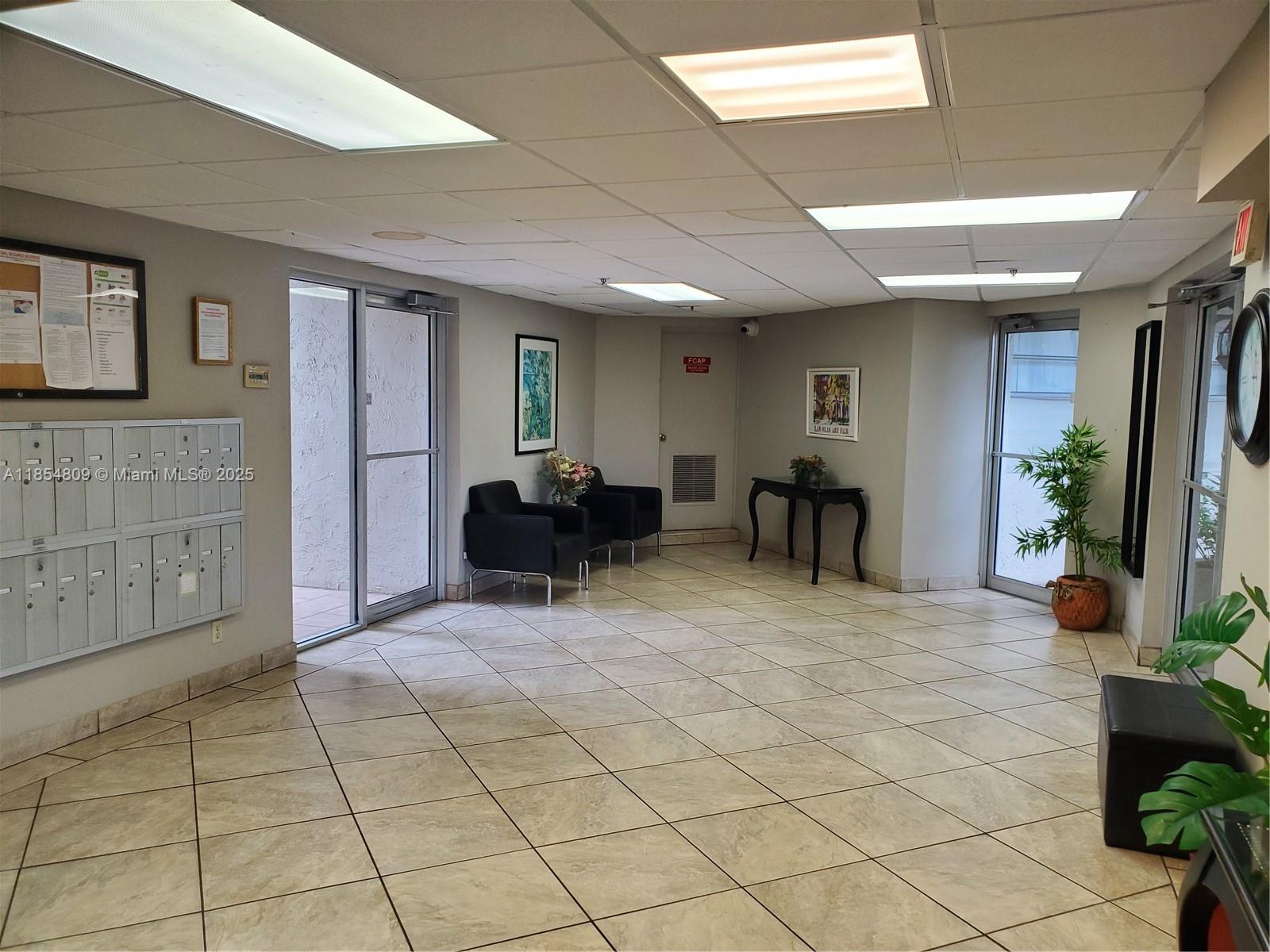 A lobby area features tiled floors, mailboxes, seating, and glass doors leading to the exterior — 3940 Inverrary Blvd # A, Lauderhill FL 33319, LAUDERHILL, FL