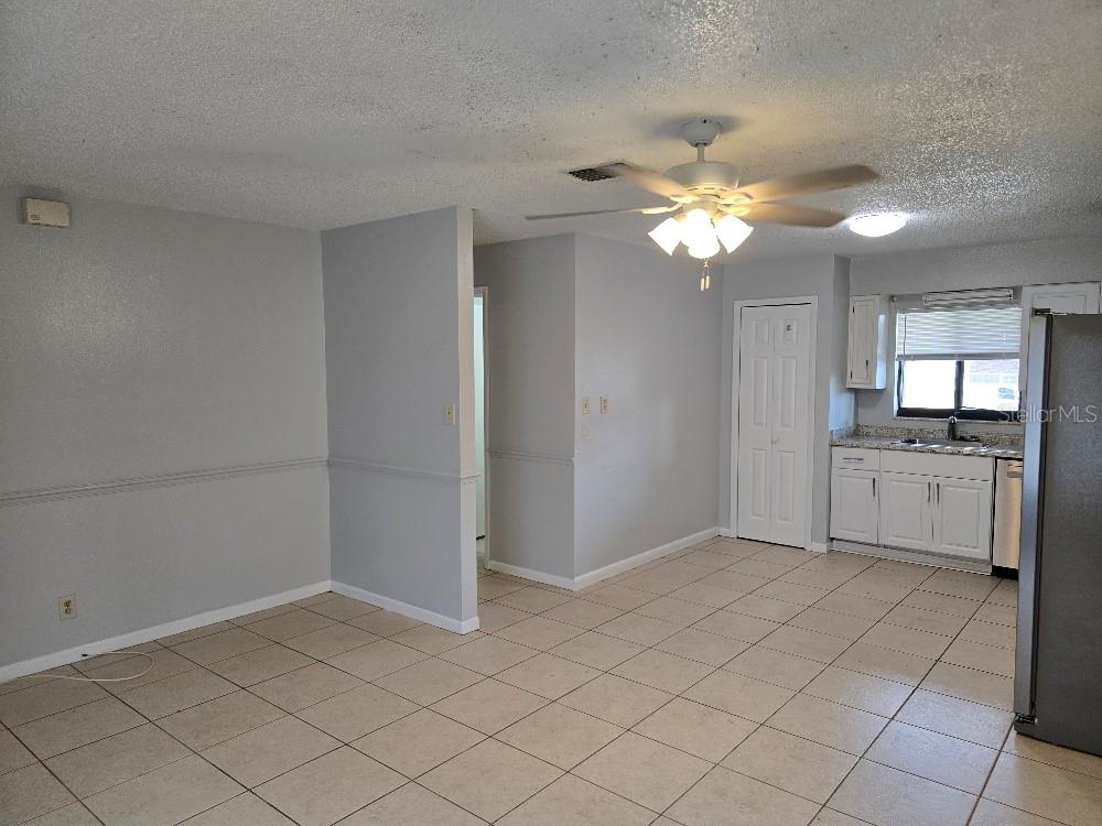 An open-concept room features light gray walls, beige tile flooring, and an adjacent kitchen area — 780 E NORTH STREET, BARTOW, FL