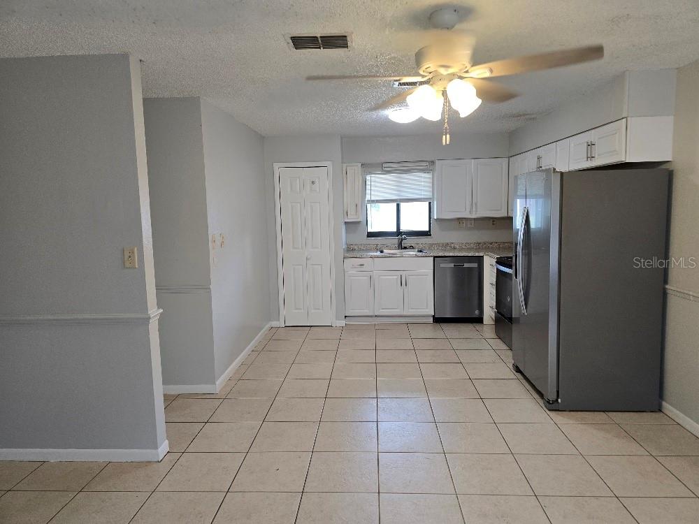 A kitchen features white cabinets, stainless steel appliances, tile flooring, and a double-door pantry — 780 E NORTH STREET, BARTOW, FL