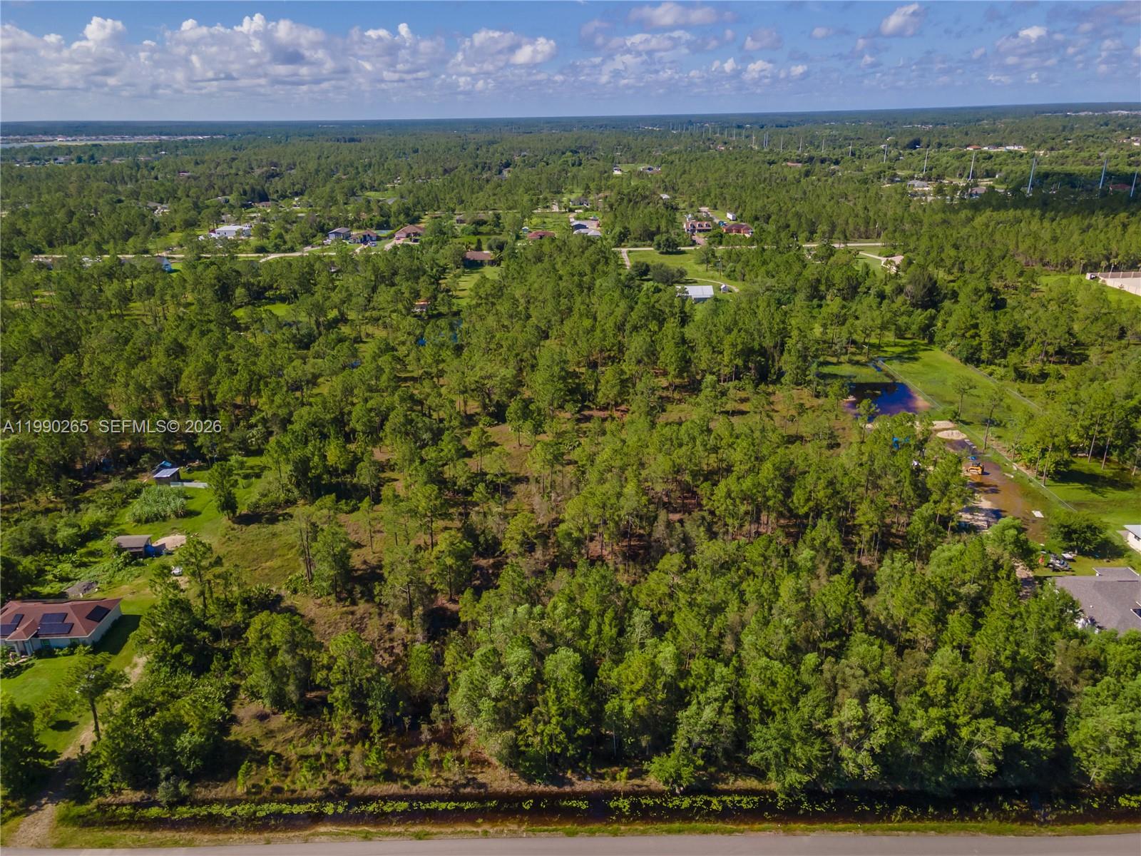 An aerial view shows a densely wooded lot with a canal in the foreground — 50th AVE NE Everglades BLVD N, Naples FL 34120, NAPLES, FL
