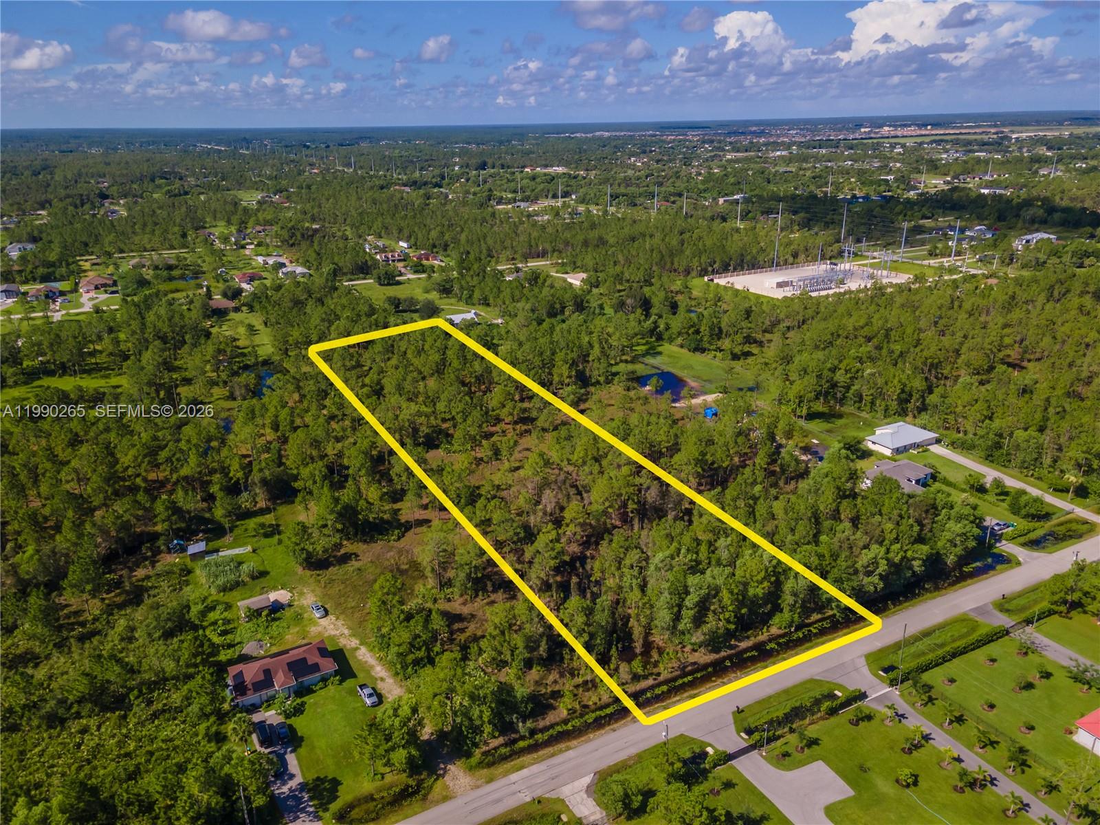 An aerial view shows a rectangular, wooded vacant lot outlined in yellow along a road — 50th AVE NE Everglades BLVD N, Naples FL 34120, NAPLES, FL