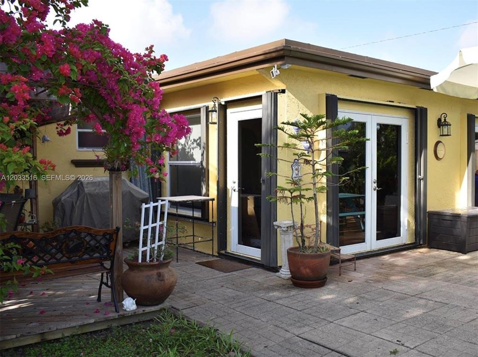 A yellow house exterior features a patio, a bougainvillea tree, and glass double doors — 4415 Tyler St # 4415, Hollywood FL 33021, HOLLYWOOD, FL