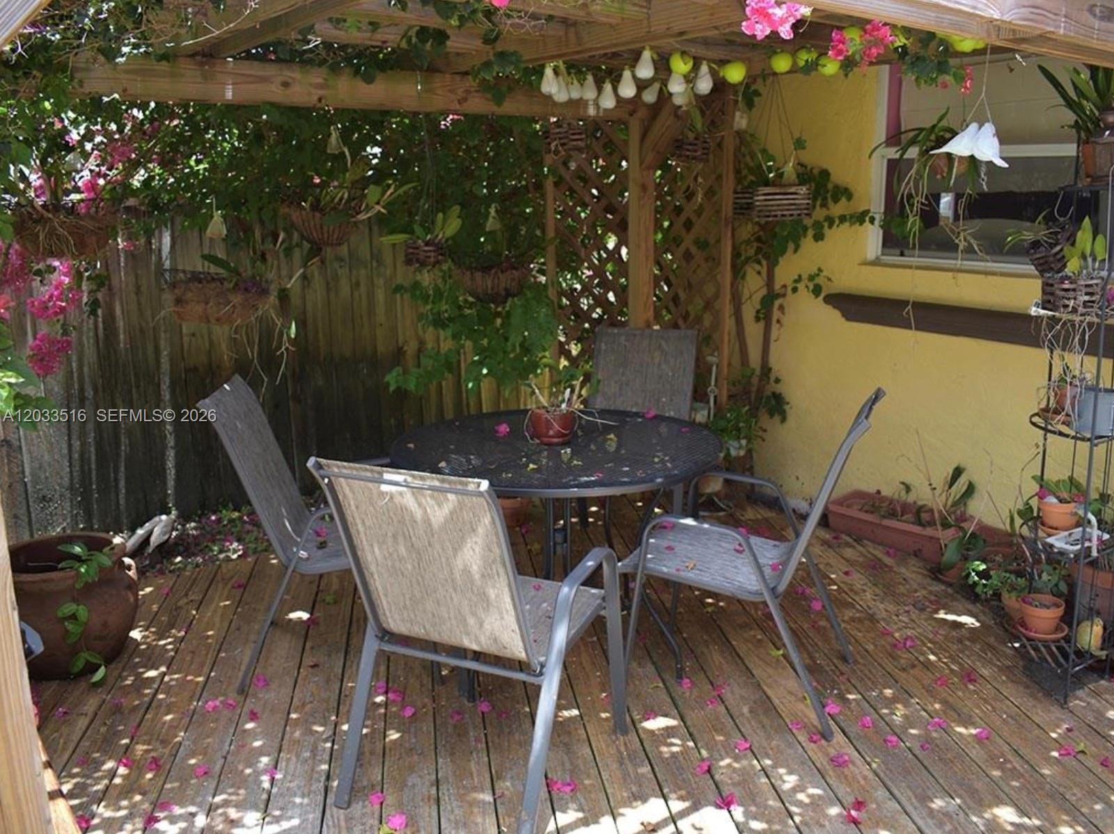 A wooden deck features a round metal table with four chairs under a pergola — 4415 Tyler St # 4415, Hollywood FL 33021, HOLLYWOOD, FL