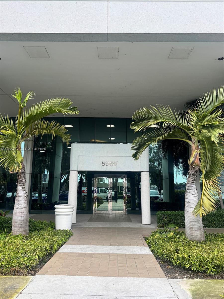 A paved walkway leads to the glass entrance of a building marked with the number 5959 — 5959 Waterford District Dr # 200, Miami FL 33126, MIAMI, FL