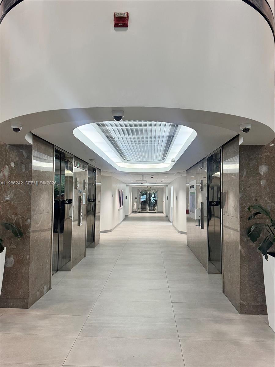 A modern elevator lobby features marble walls, tiled floors, and a recessed ceiling light fixture — 5959 Waterford District Dr # 200, Miami FL 33126, MIAMI, FL