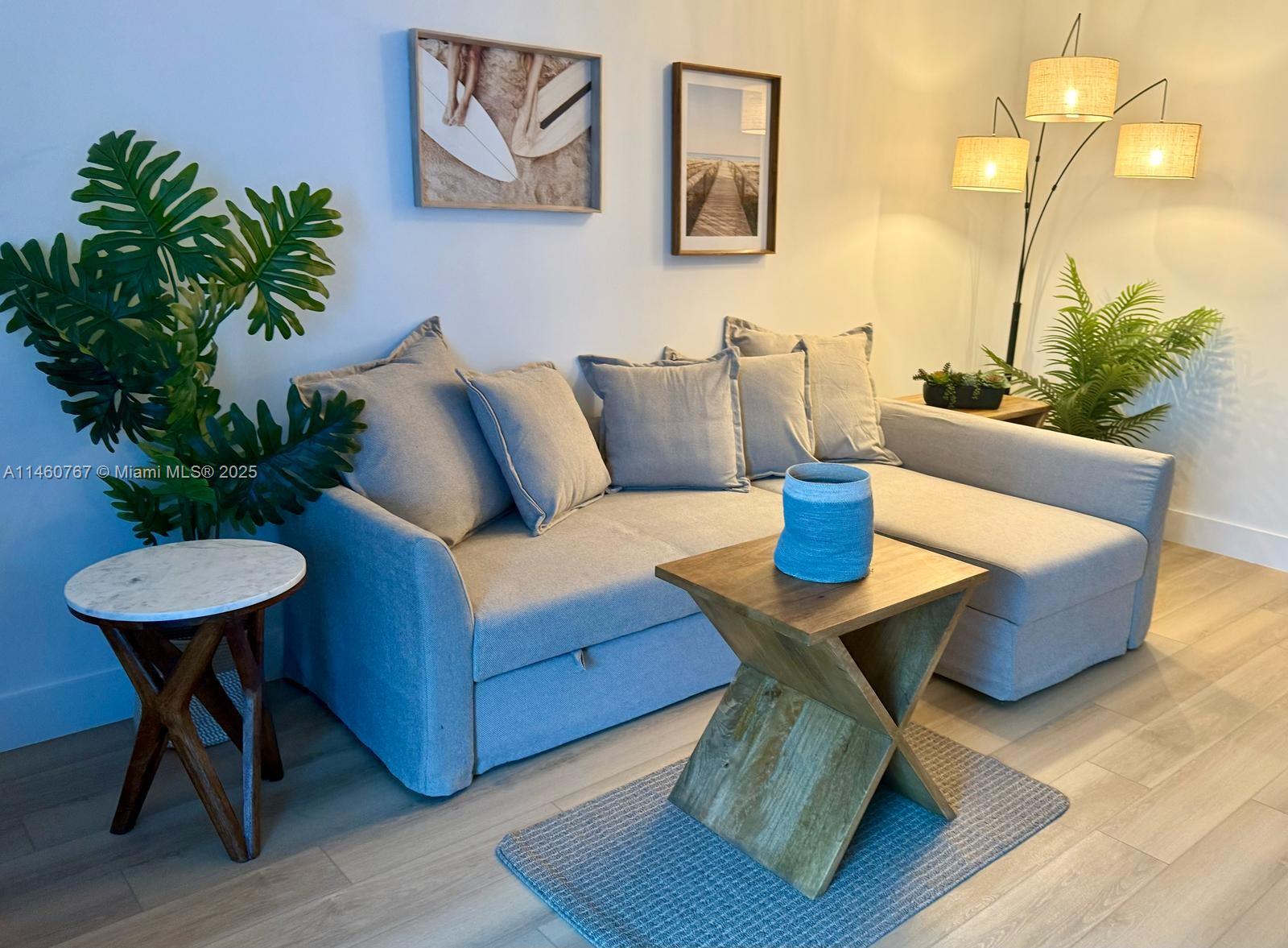 A living room features a gray sectional sofa, a wooden side table, and floor lamps — 2301 Collins Ave # 1121, Miami Beach FL 33139, MIAMI BEACH, FL