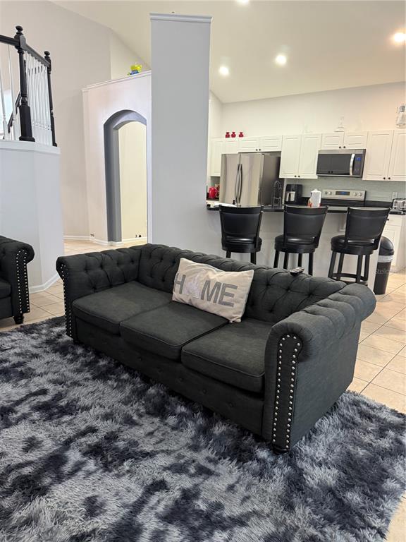 A living room with a tufted gray sofa faces an open kitchen with bar seating — 8105 SUN PALM DRIVE, KISSIMMEE, FL