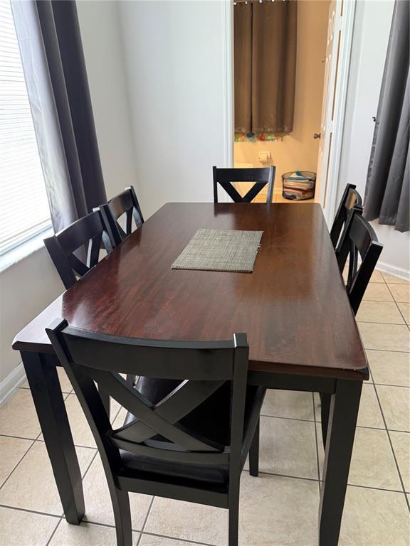 A dining room features a dark wood table with six black X-back chairs on tile — 8105 SUN PALM DRIVE, KISSIMMEE, FL