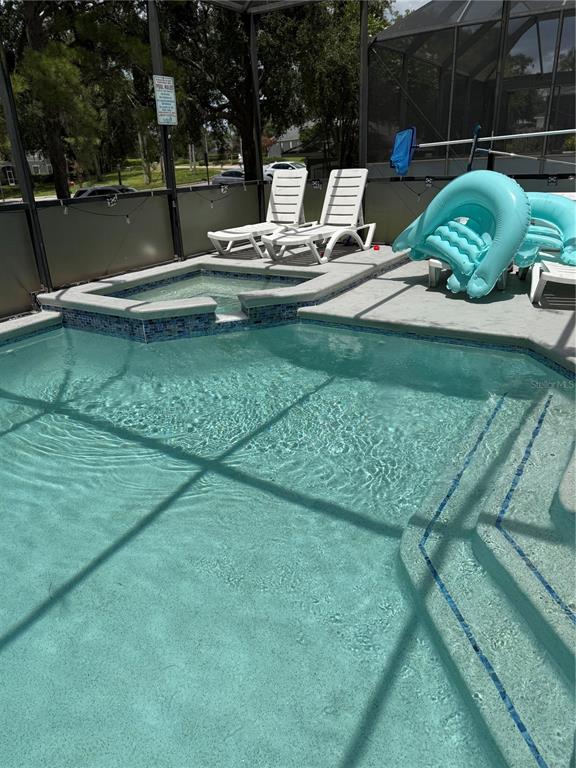 A swimming pool with an attached spa and two lounge chairs on the deck — 8105 SUN PALM DRIVE, KISSIMMEE, FL