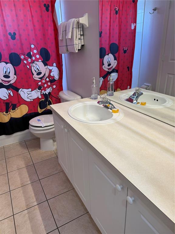 A bathroom features a Mickey Mouse shower curtain, a white vanity, and tiled flooring — 8105 SUN PALM DRIVE, KISSIMMEE, FL