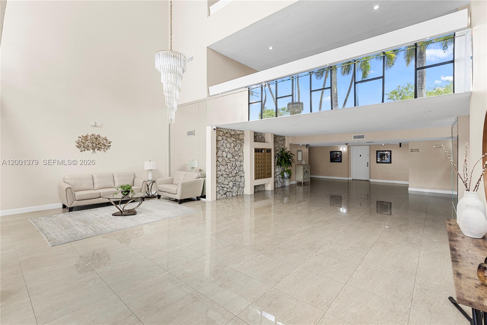 A spacious lobby features high ceilings, a crystal chandelier, tile floors, and a stone wall — 16251 Golf Club Rd # 311, Weston FL 33326, WESTON, FL