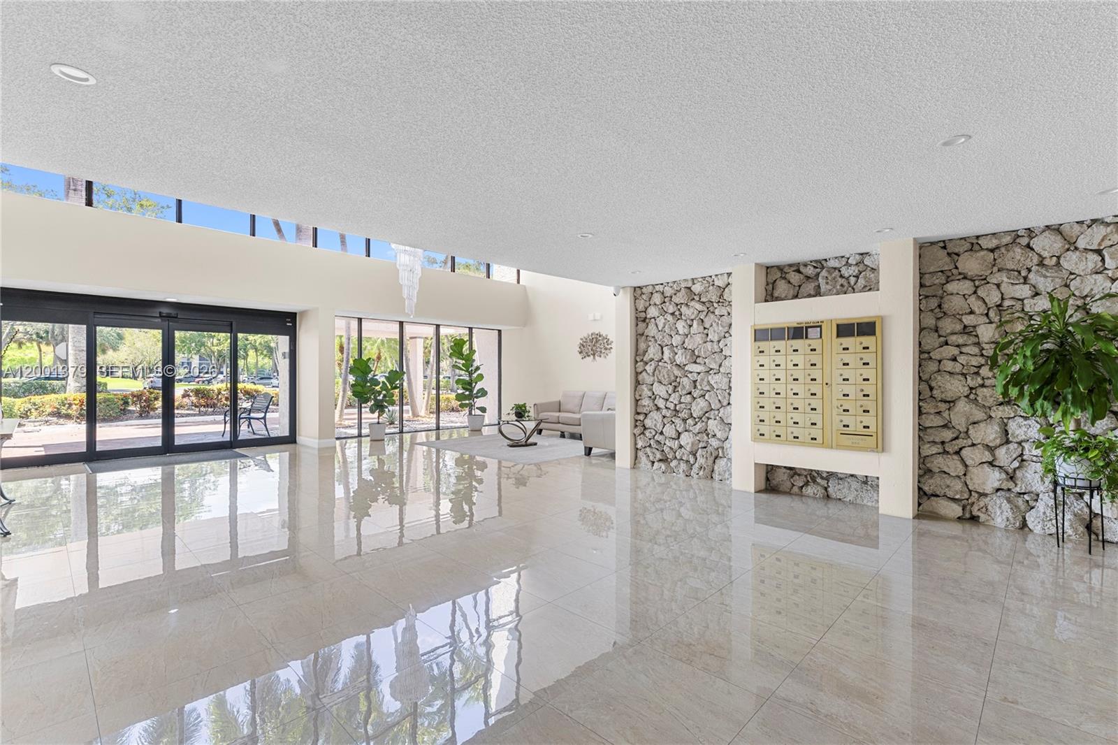 A bright lobby features polished tile floors, a stone accent wall, and a mail station — 16251 Golf Club Rd # 311, Weston FL 33326, WESTON, FL