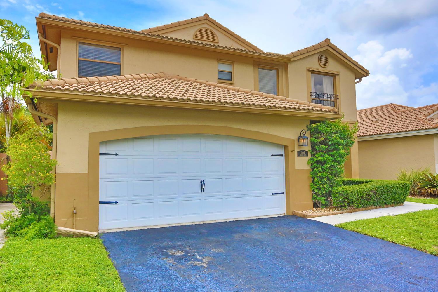 A two-story house with a tan stucco exterior, a white garage door, and a tiled roof — 15061 Durham Lane, Davie FL 33331, DAVIE, FL
