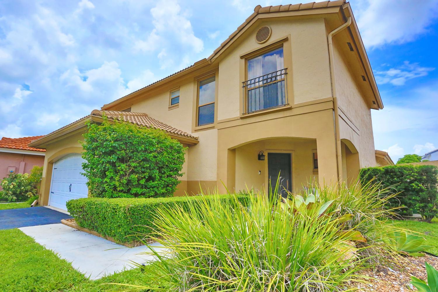 A two-story tan house with a garage, a small balcony, and a landscaped front yard — 15061 Durham Lane, Davie FL 33331, DAVIE, FL