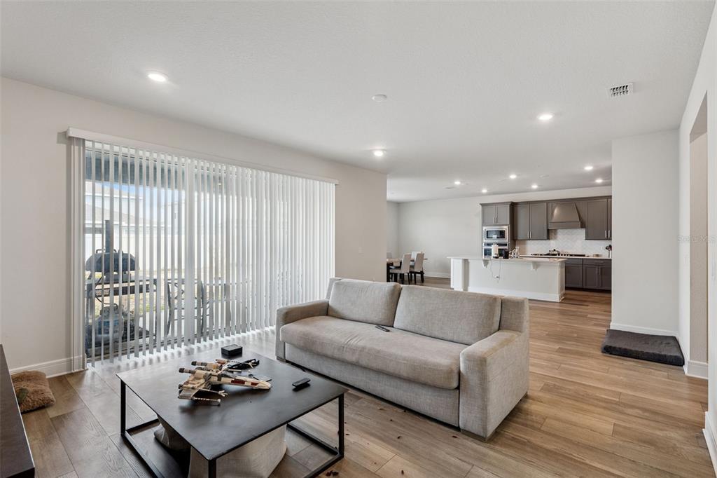 A living room with a grey sofa and coffee table opens to a kitchen area — 4008 MEANDERING BAY DRIVE, APOPKA, FL