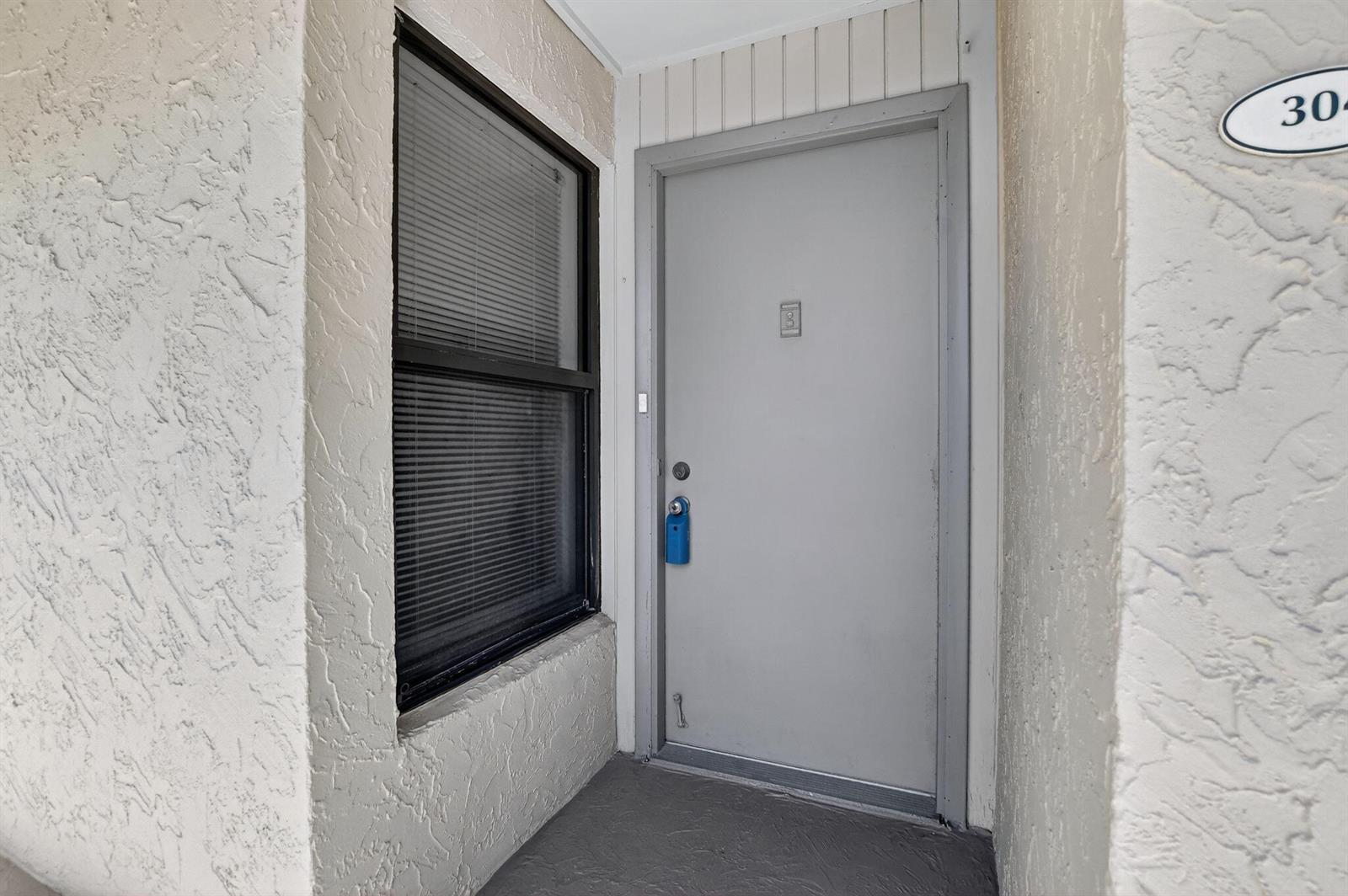 A gray door with a blue lockbox sits next to a window on a porch — 11 Royal Palm Way # 3040, Boca Raton FL 33432, BOCA RATON, FL