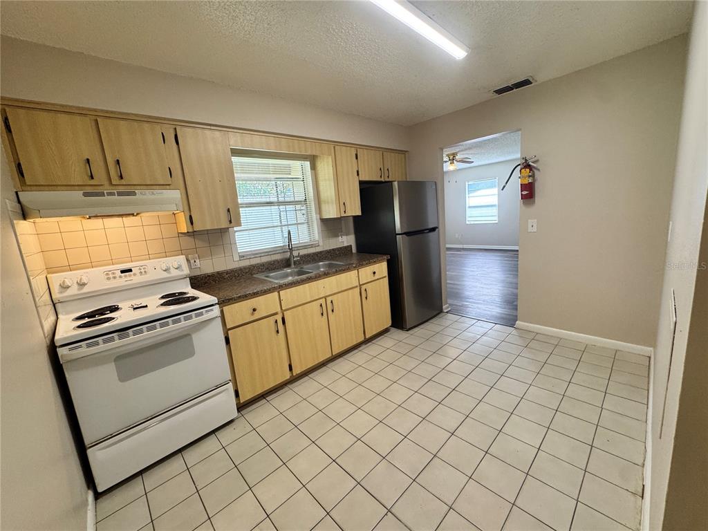 A kitchen with light wood cabinets, white appliances, and tiled flooring — 1001 CRAWFORD STREET, LEESBURG, FL