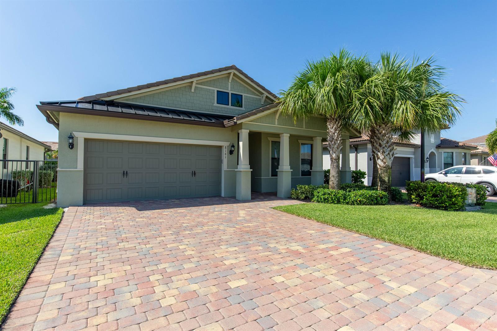 A single-story house with a green exterior, a paver driveway, and two palm trees — 8161 Hanoverian Drive, Lake Worth FL 33467, LAKE WORTH, FL