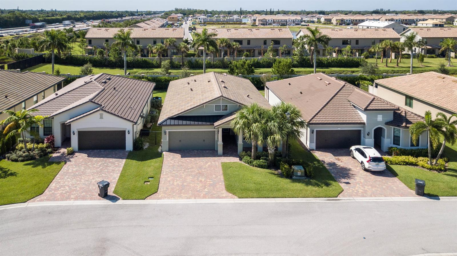 An aerial view shows three suburban houses with paved driveways and palm trees — 8161 Hanoverian Drive, Lake Worth FL 33467, LAKE WORTH, FL