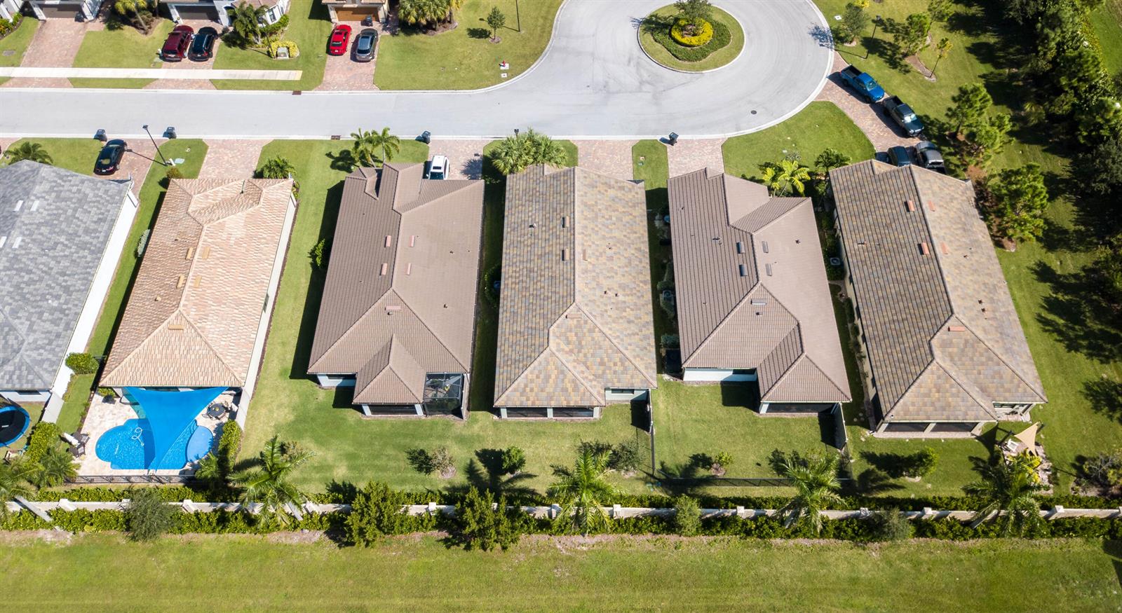 An aerial view shows a row of suburban houses with tiled roofs and backyard pools — 8161 Hanoverian Drive, Lake Worth FL 33467, LAKE WORTH, FL