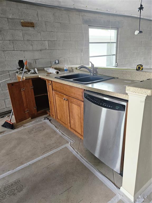 A kitchen under renovation features wood cabinets, a stainless steel dishwasher, and exposed block walls — 6800 PLACIDA ROAD UNIT 290, ENGLEWOOD, FL