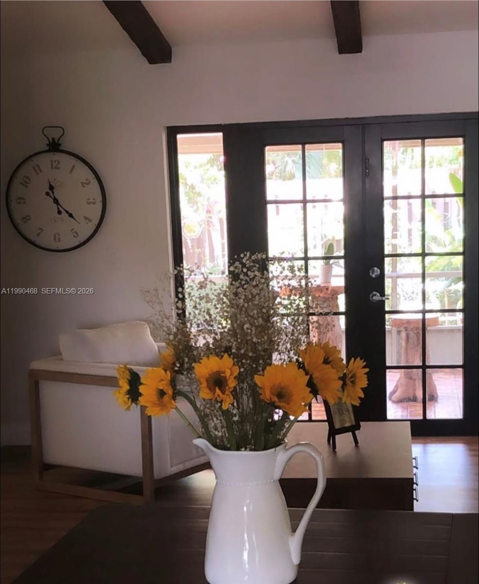 A white pitcher with sunflowers sits on a table before a chair and glass doors — 11269 SW 116th Ter # 11269, Miami FL 33176, MIAMI, FL