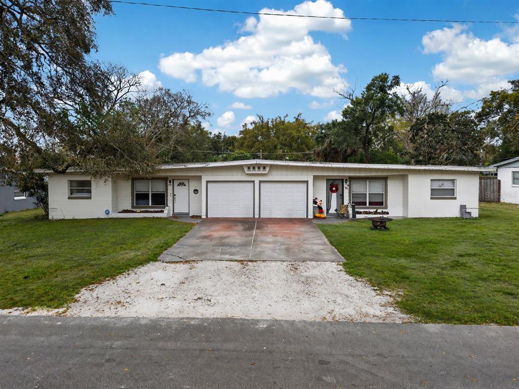 A single-story duplex with white siding, two garage doors, and a shared concrete driveway — 70 GRIGGS AVENUE, CASSELBERRY, FL