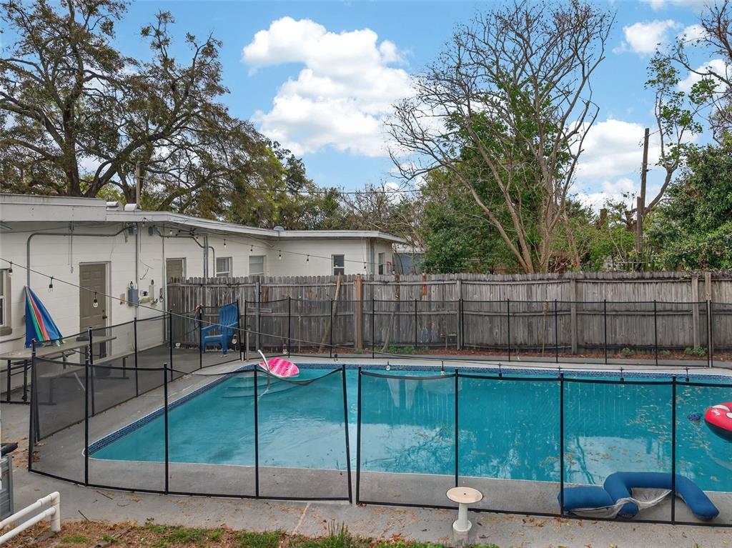 A backyard features a rectangular swimming pool enclosed by a black mesh safety fence — 70 GRIGGS AVENUE, CASSELBERRY, FL