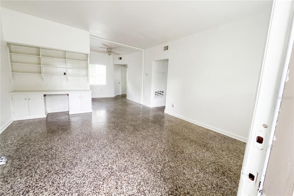 An interior view of a room with white walls, built-in shelving, and speckled flooring — 70 GRIGGS AVENUE, CASSELBERRY, FL