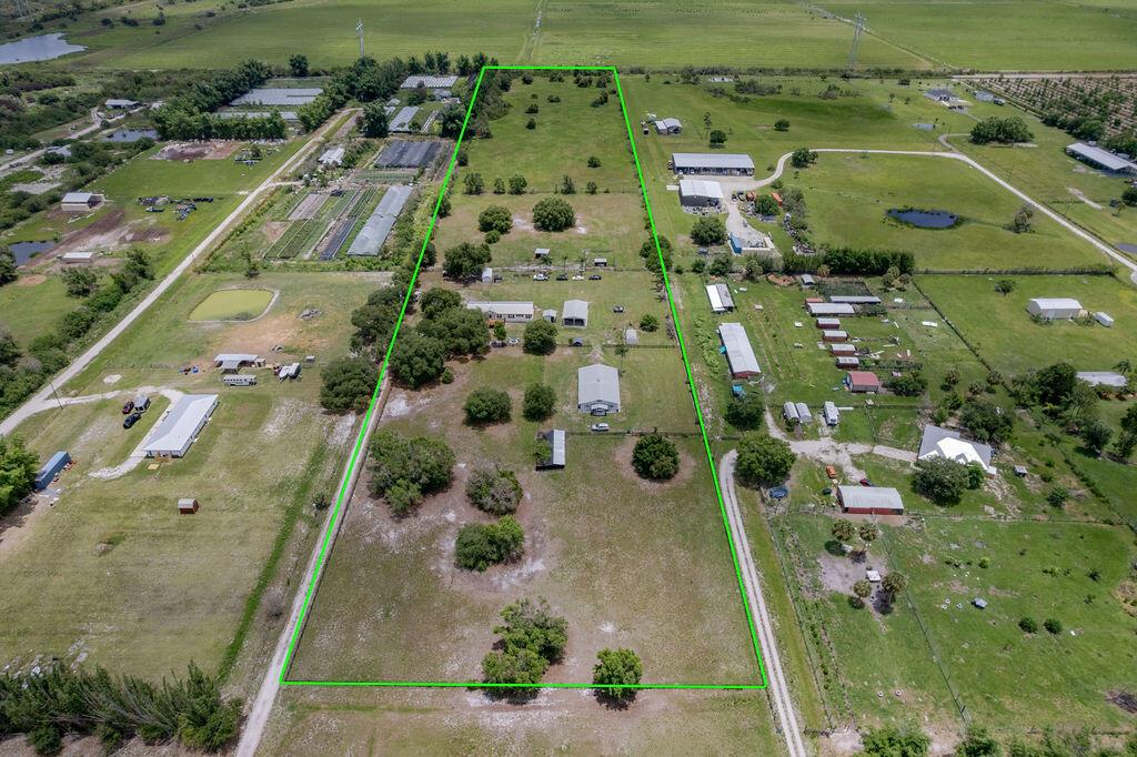 An aerial view shows a long, rectangular parcel of land outlined in green — 11301 SW Fox Brown Road, FL 34956, FL