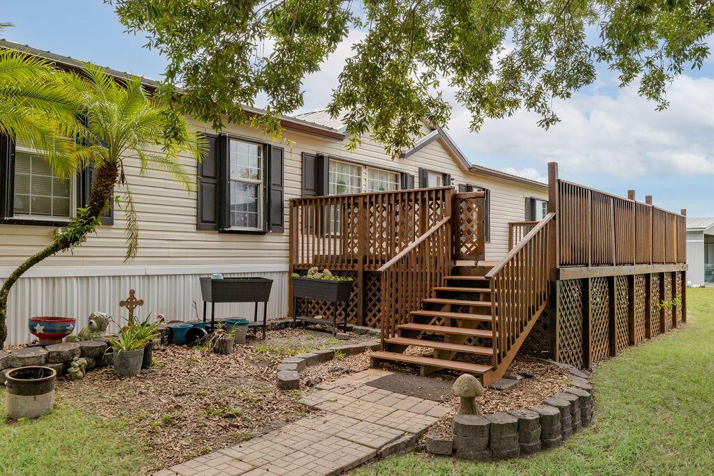 A mobile home features a large wooden deck with stairs leading to a brick walkway — 11301 SW Fox Brown Road, FL 34956, FL