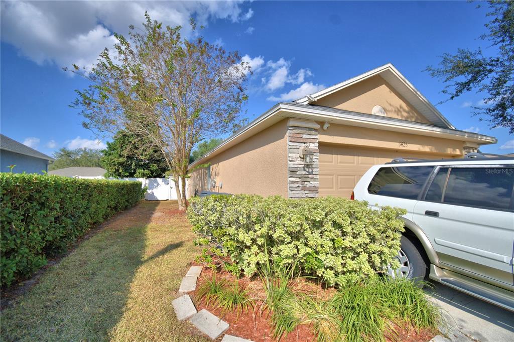 A single-story house with a tan stucco exterior, a two-car garage, and a large tree — 3425 STONEWAY DRIVE, LAKELAND, FL